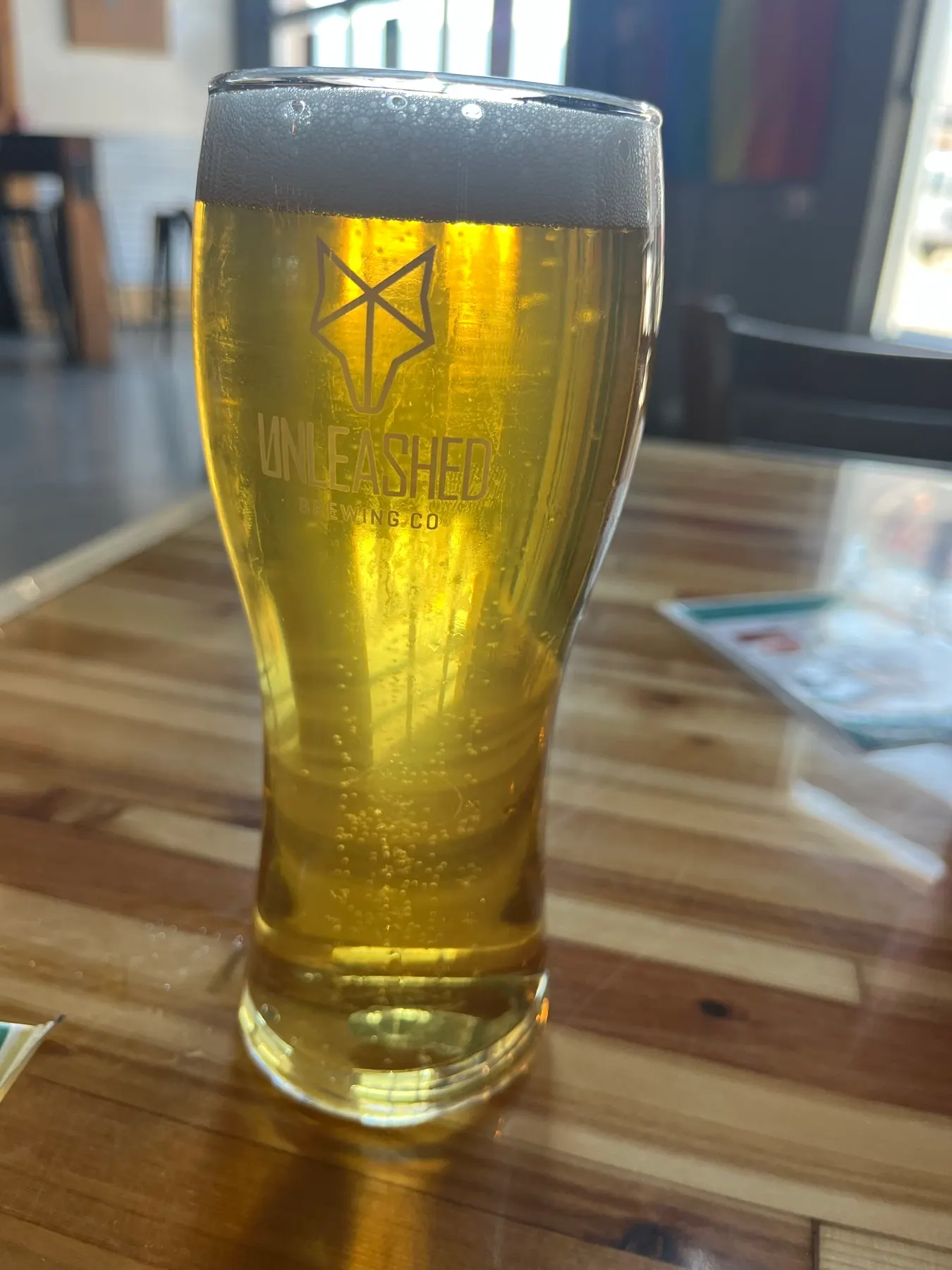 A glass of beer carrying the Unleashed Brewing logo