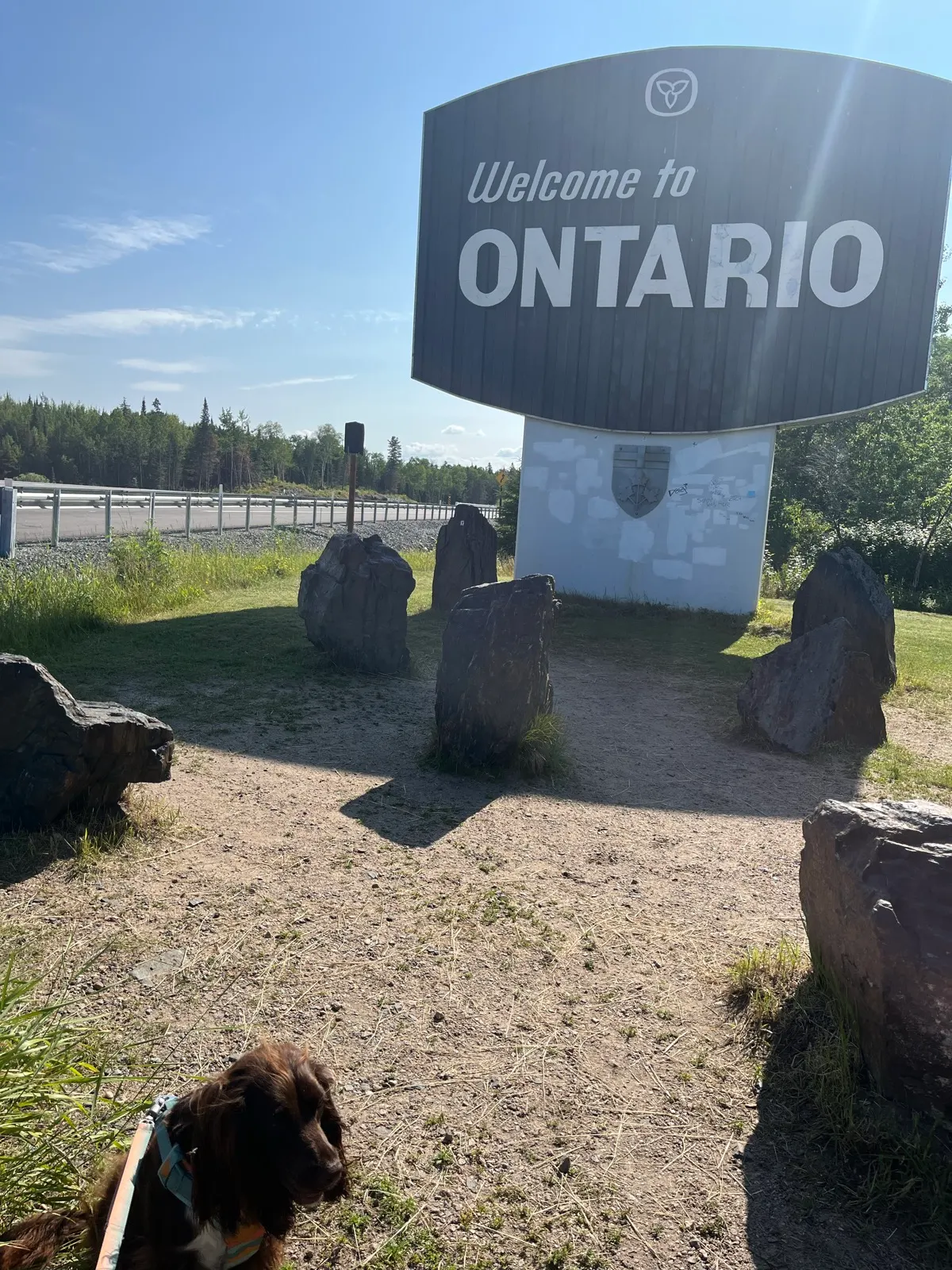 Tilly beside the Welcome to Ontario sign at the Manitoba border